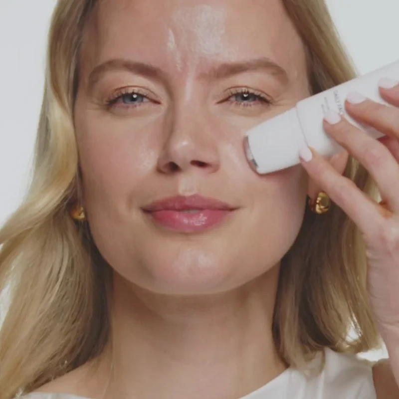 Blonde model applying Daily Face SPF 40 with its cooling rollerball for a radiant, sun-protected summer glow.