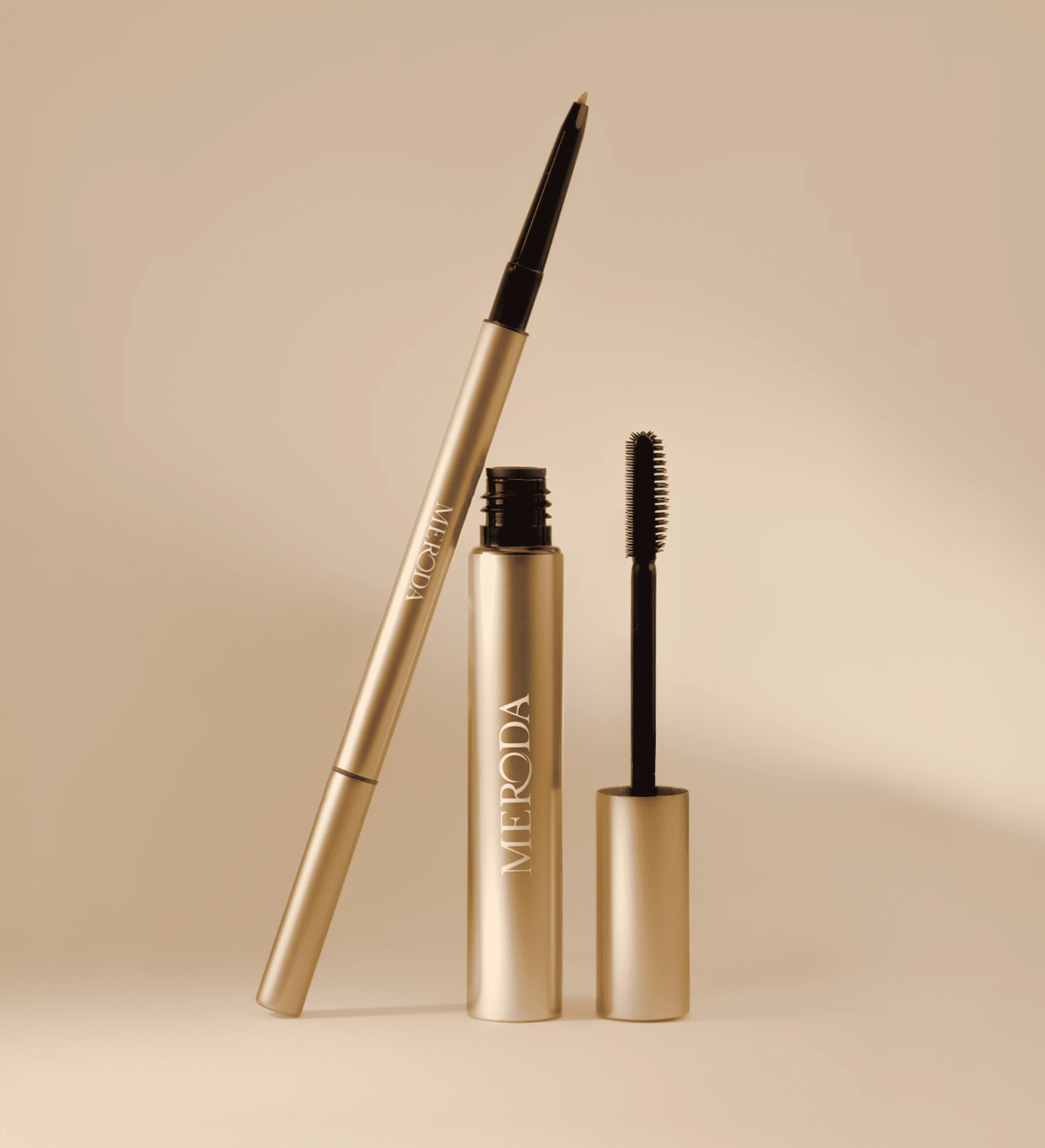 The Brow Defining Duo featuring The Precision Brow Pencil and The Precision Brow Gel in gold on a neutral beige background.