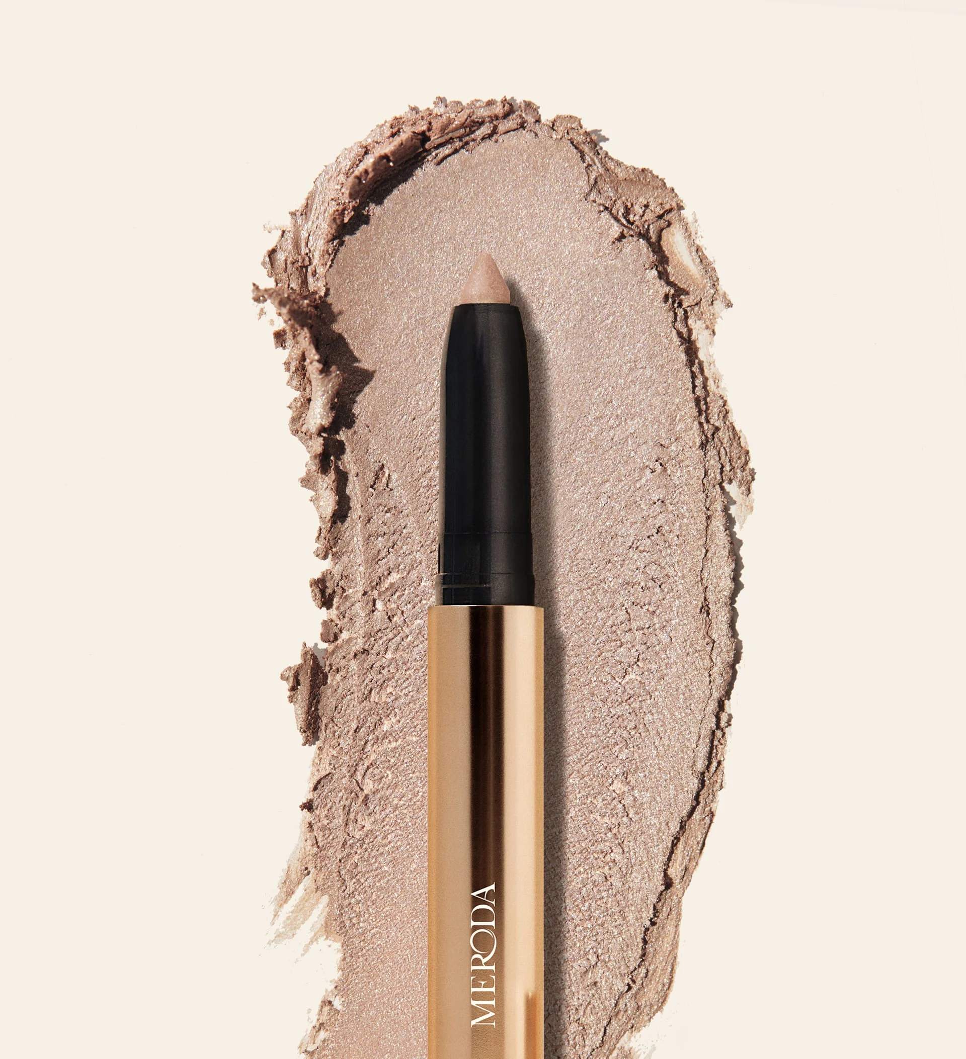Meroda Cosmetics Eye Perfecting Shimmer Stick in Champagne with a luminous cream texture swatch for a radiant finish.