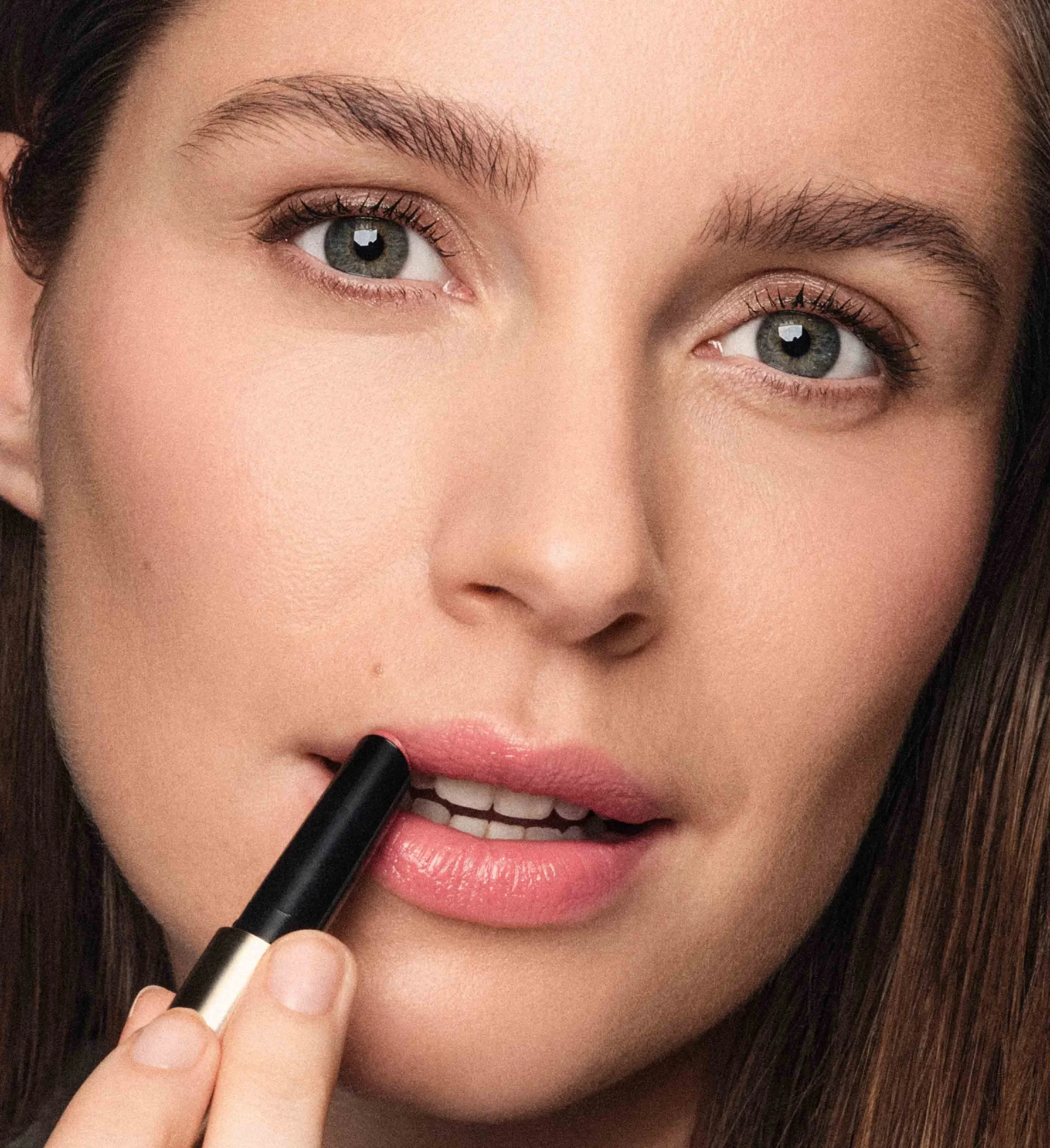 Woman applying Meroda Cosmetics Hydrating Lip Tint in Peachy Rose for a fresh, natural look.
