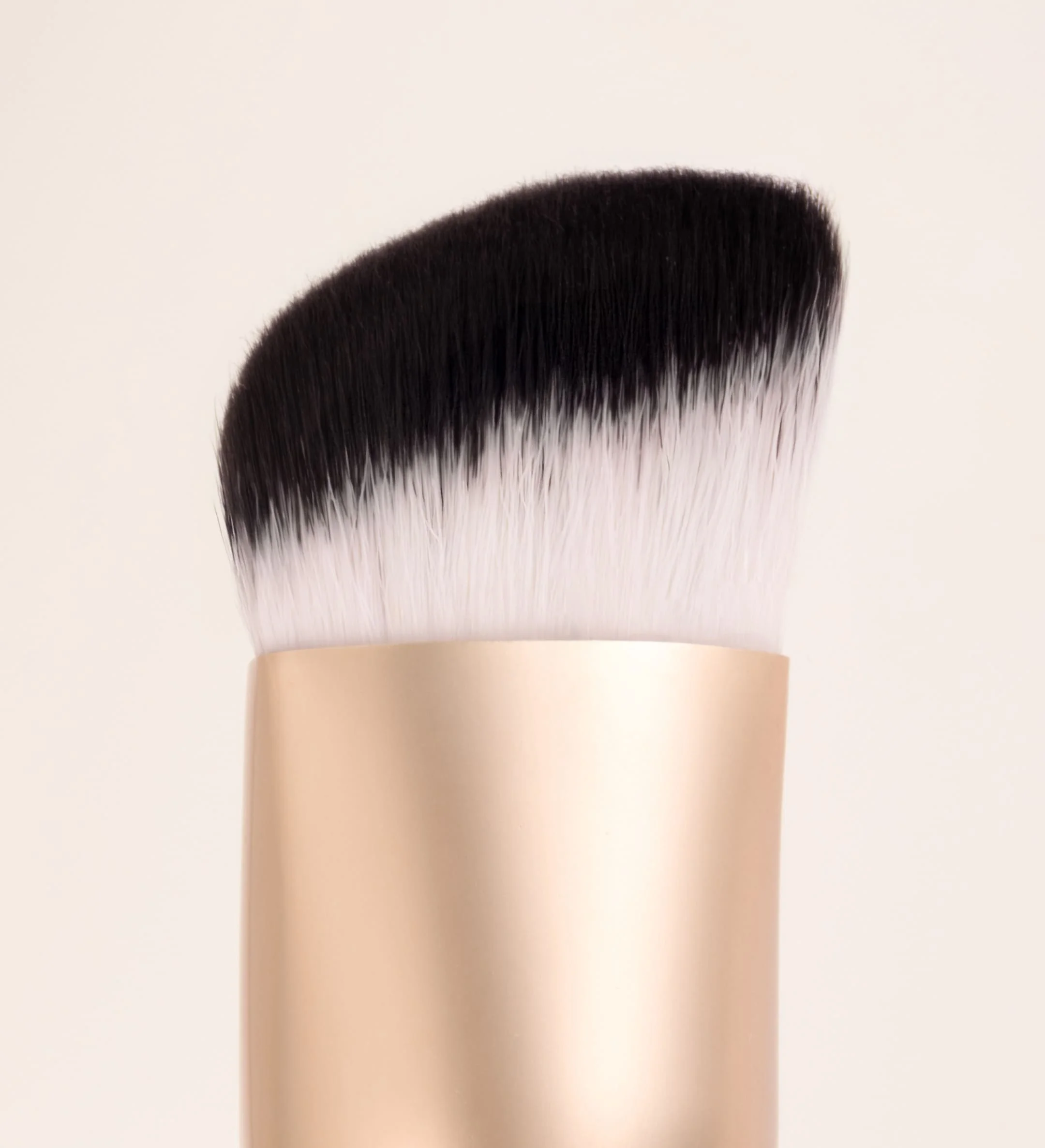 The Essential Brush by Meroda Cosmetics featuring a unique triangular shape and dense bristles for seamless blending.