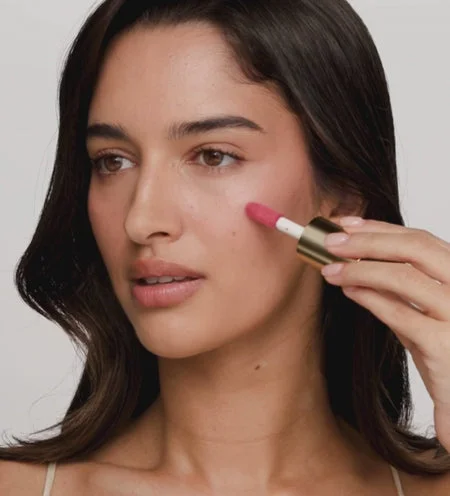 Model blends pink Vibrant Cheek Blush using a brush for a healthy glow from The Valentines Bundle.