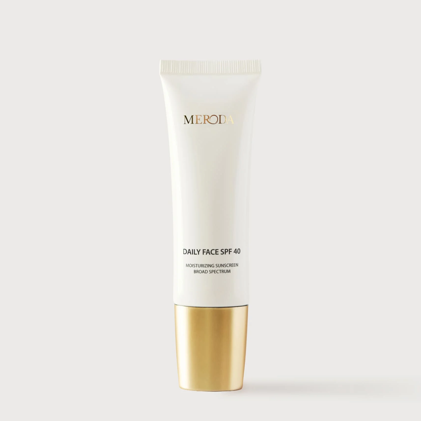 Daily Face SPF 40 white tube with a metallic gold cap and minimalist black and gold typography.